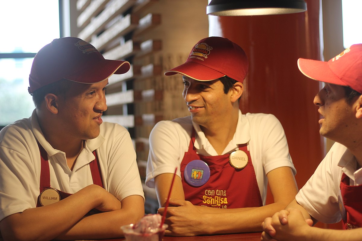 Foto de tres amigos conversando donde uno tiene discapacidad