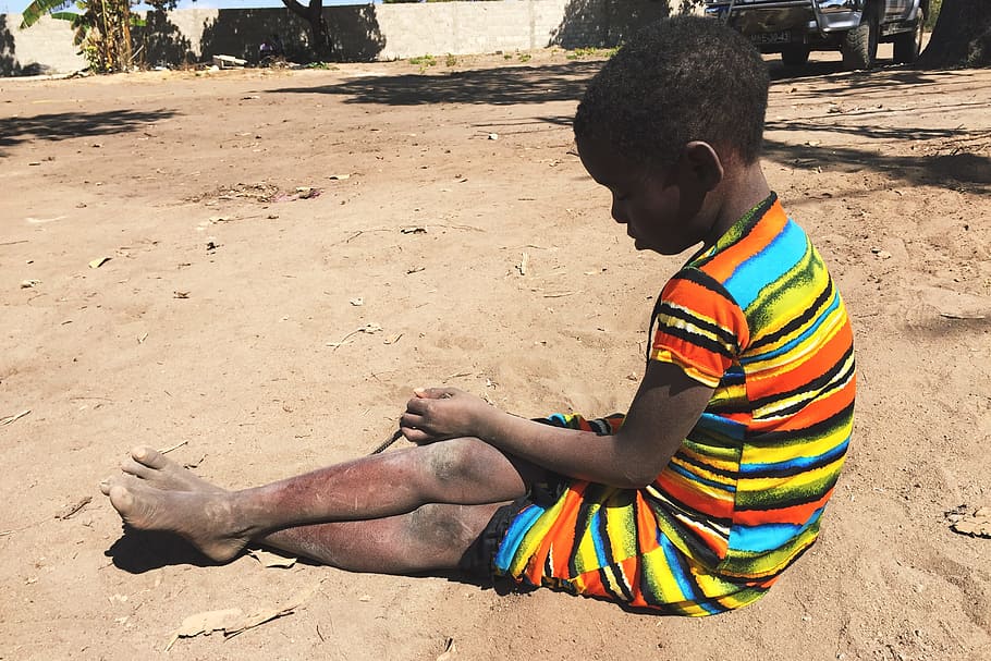 Imagen de niño afro, pobre y sentado en el piso.